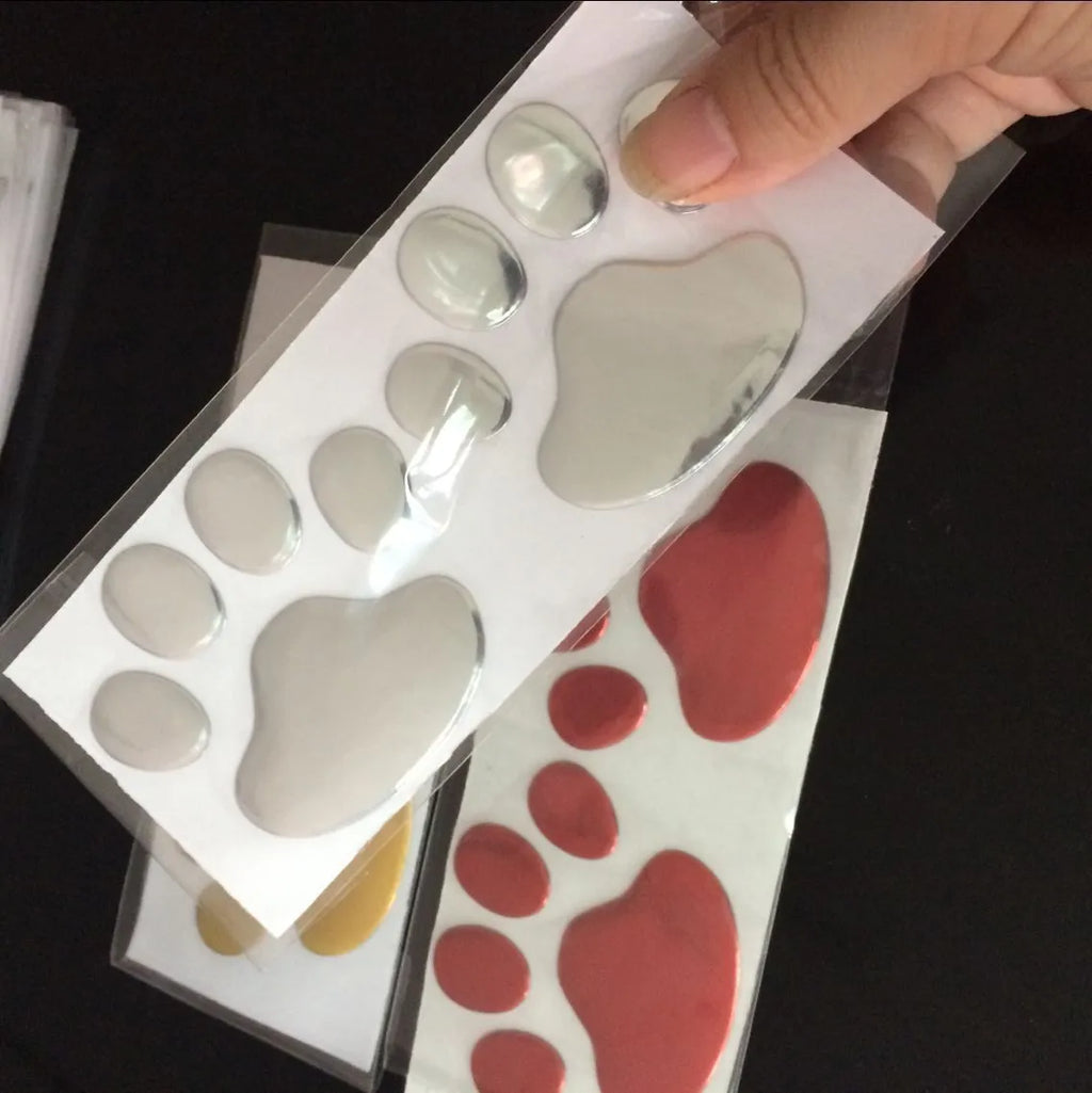 PVC car bumper sticker with hand-brushed dog footprints pattern in red, silver, gold, or black, 7cm long.
