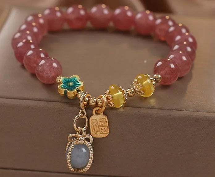 Red strawberry quartz beaded bracelet with silver-toned alloy charms and clear rhinestone details.