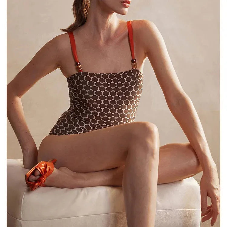 Women's dotted one-piece swimsuit with a matching wrap skirt laid flat.