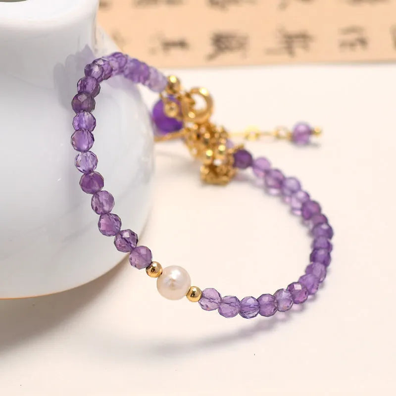 Close-up of a Chinese style women's bracelet with diamond-shaped amethyst crystal beads and an electroplated finish.