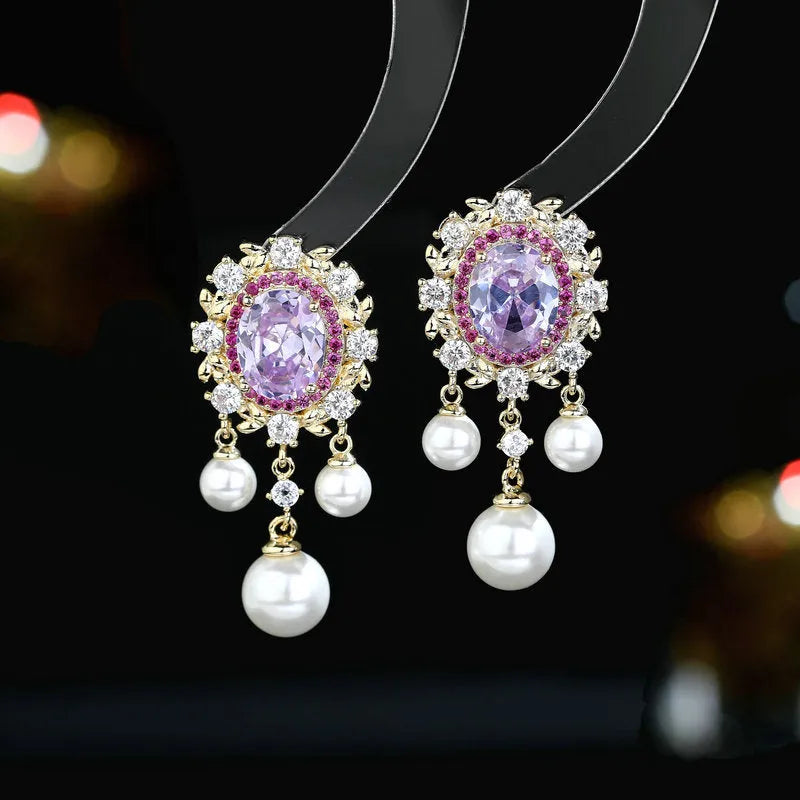 A pair of geometric ellipse-shaped drop earrings with a tassel, featuring pearls and inlaid zircon stones on copper.