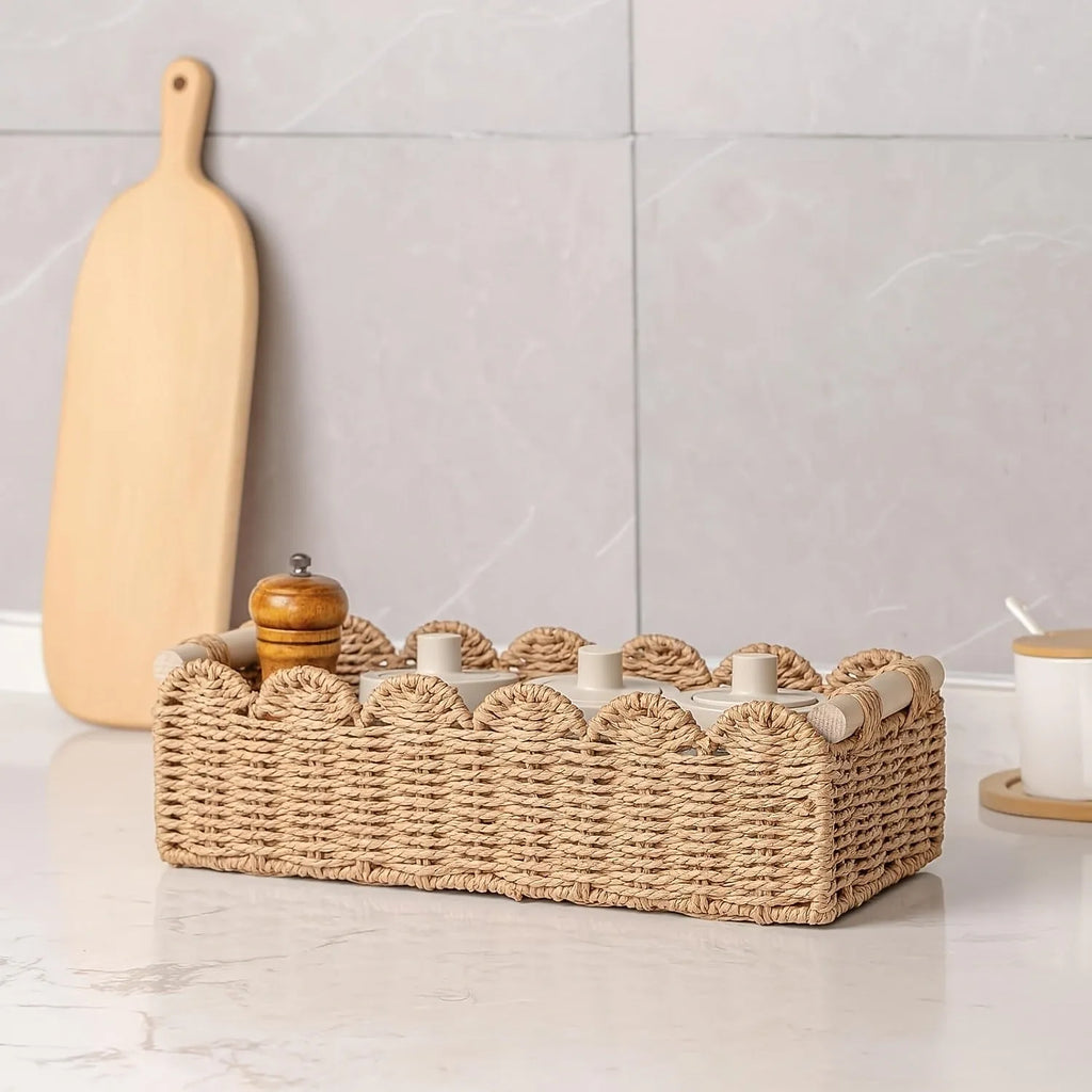 A woven paper storage basket in a neutral colour on a wooden desktop, holding remote controls and pens.