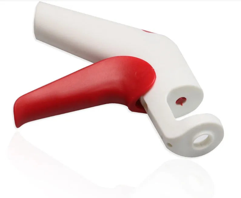Cherry stoner tool with stainless steel pitting head and white plastic handle on a wooden surface.