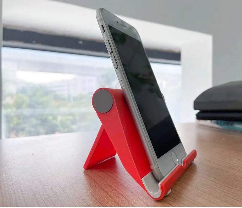 Black PE folding mobile phone stand with soft rubber grips holding a tablet at an adjustable angle