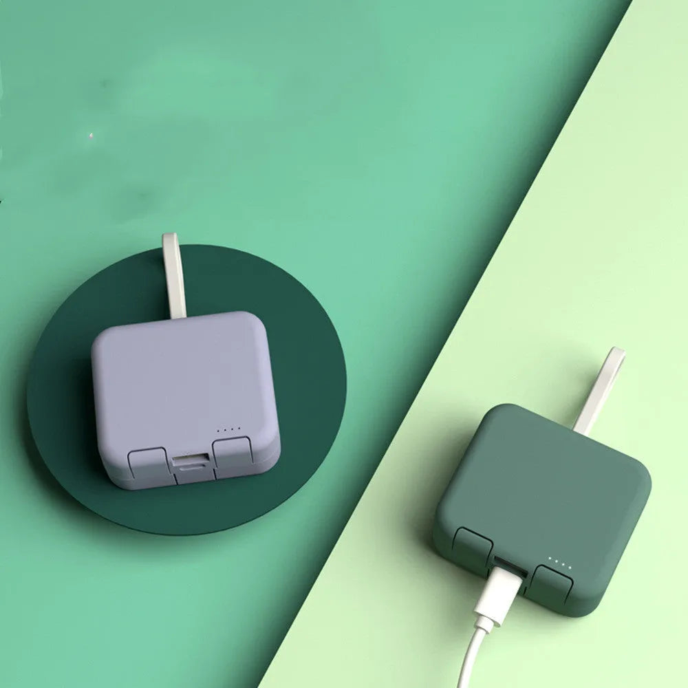 Handbag clip-on power bank in blue showing USB-A and Type-C ports, with phone propped in its integrated stand.