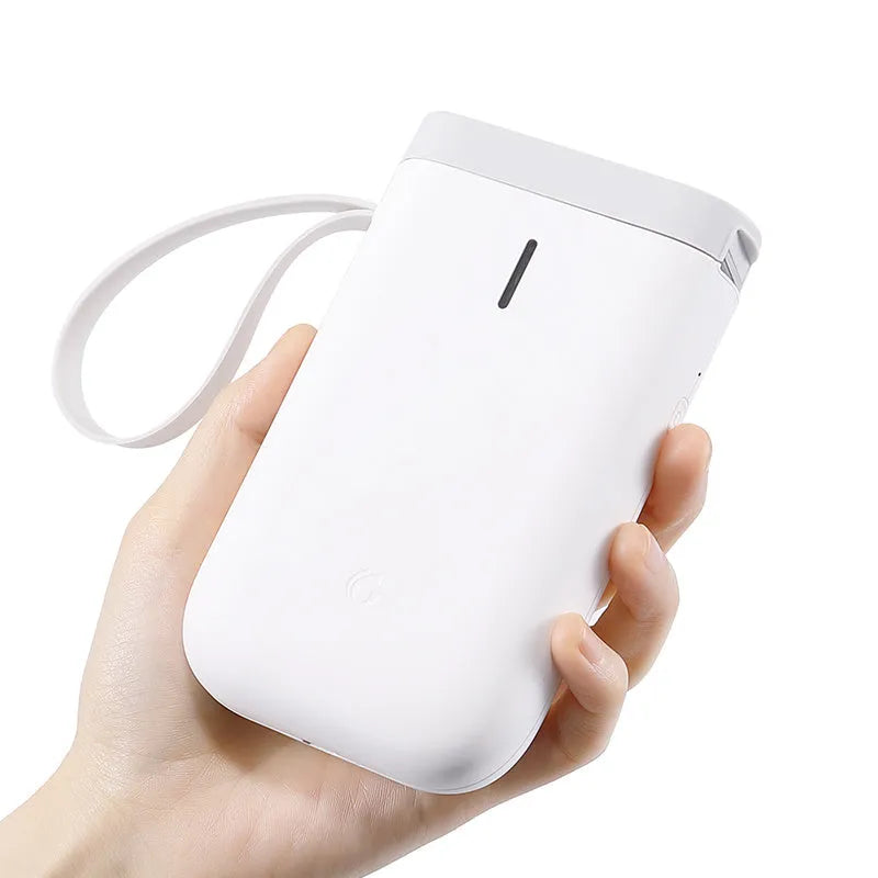 D11 compact white Bluetooth thermal label printer with USB cable and roll of label paper on a desk.