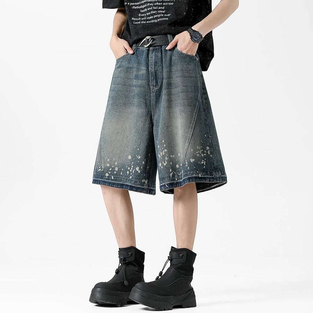 Man wearing retro blue washed denim shorts with ripped details and a straight-leg cut.