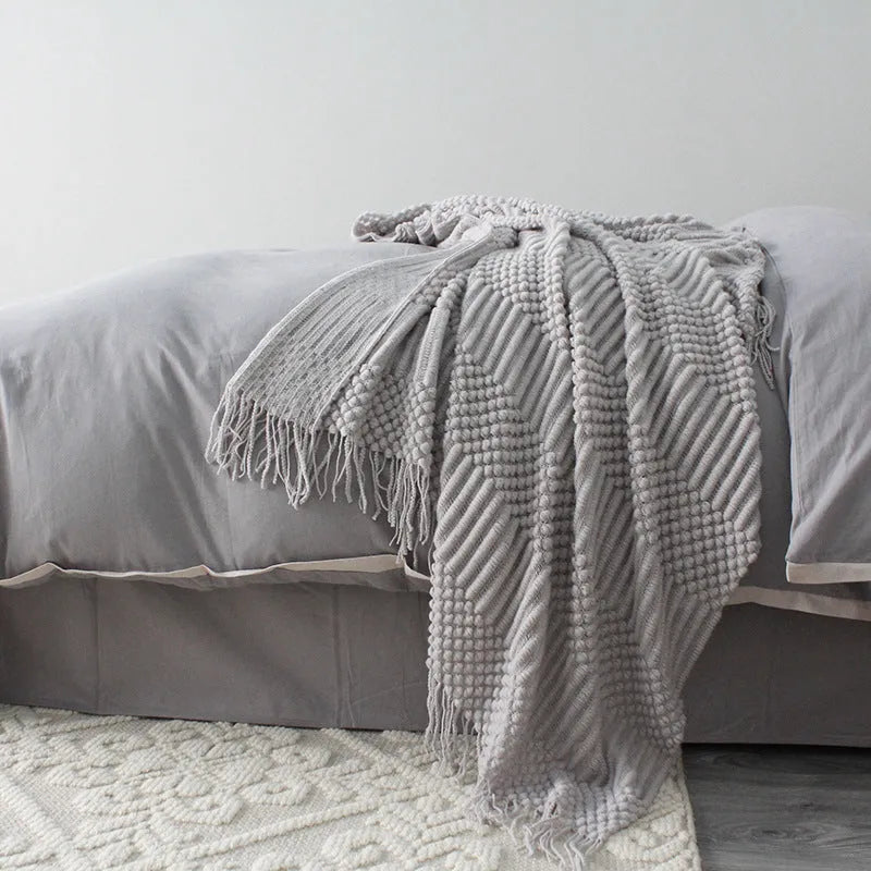 Small grey polyester nap blanket measuring 127 by 170 centimetres folded on sofa
