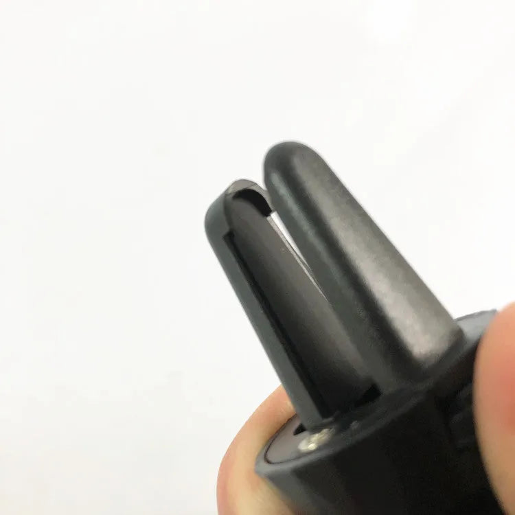 Matte black car phone holder clipped to air vent with adjustable side arms for smartphones
