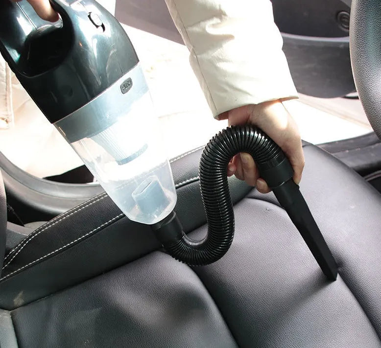 Orange 12V handheld car vacuum cleaner with nozzles on a car seat