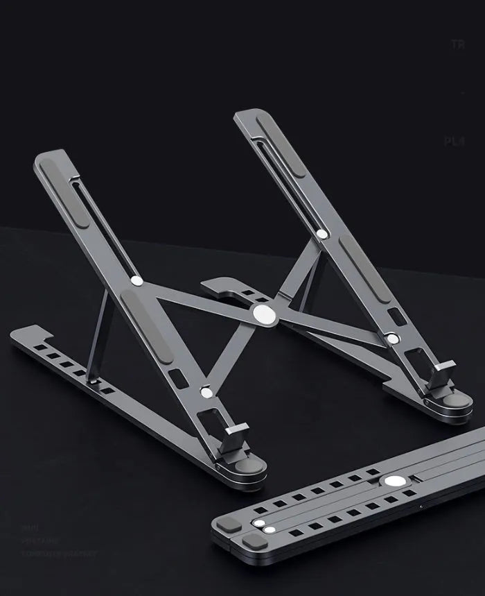 Aluminium laptop stand in silver, folded flat next to an open laptop showing its adjustable height mechanism.