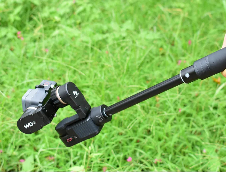Black retractable selfie stick extended with phone in holder and visible wrist strap.