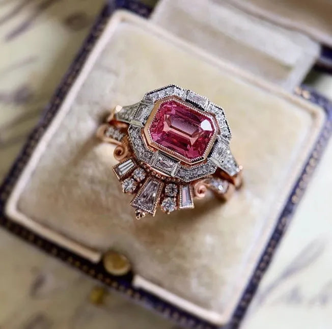 Rose gold coloured geometric women's alloy ring with a ruby detail on a white background.