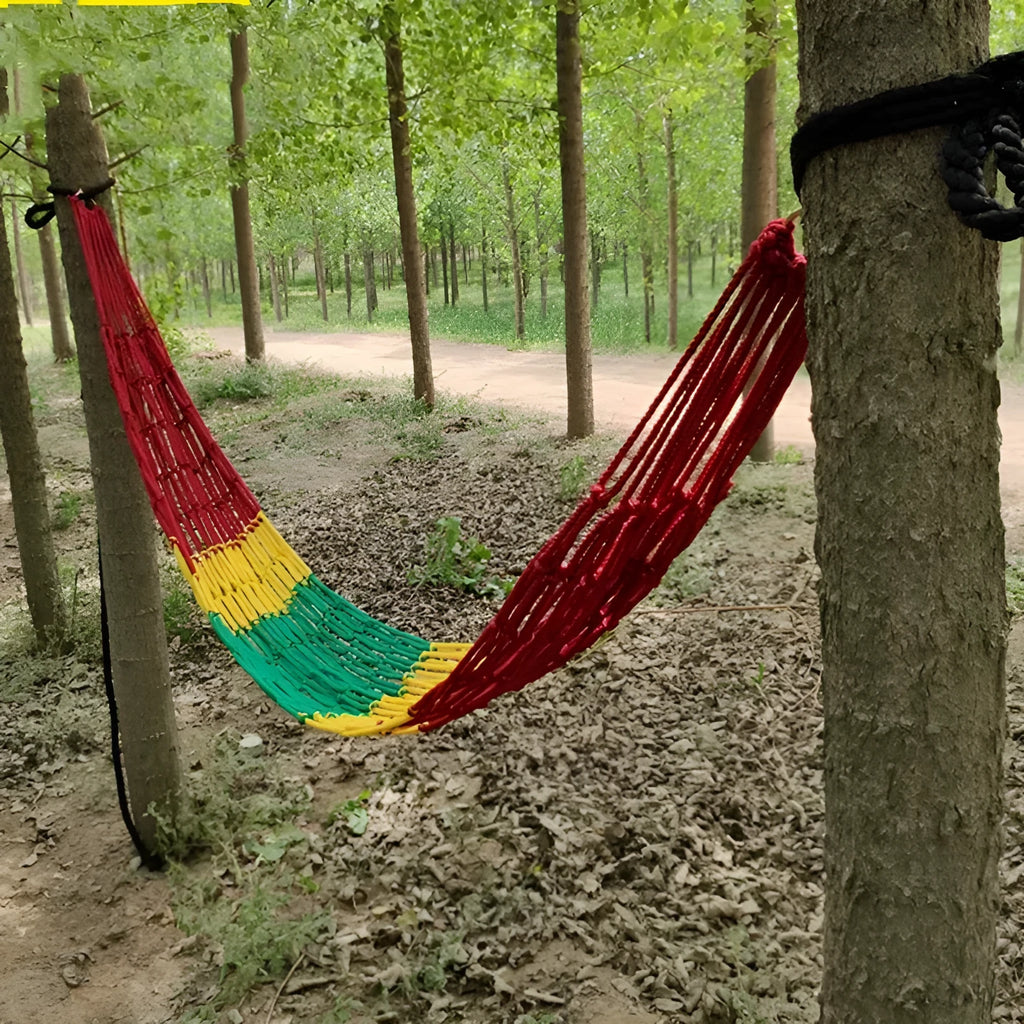 Green nylon rope mesh hammock hung between two trees showing its woven texture and length.