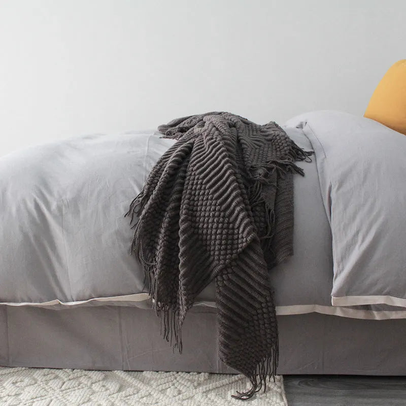 Small grey polyester nap blanket measuring 127 by 170 centimetres folded on sofa