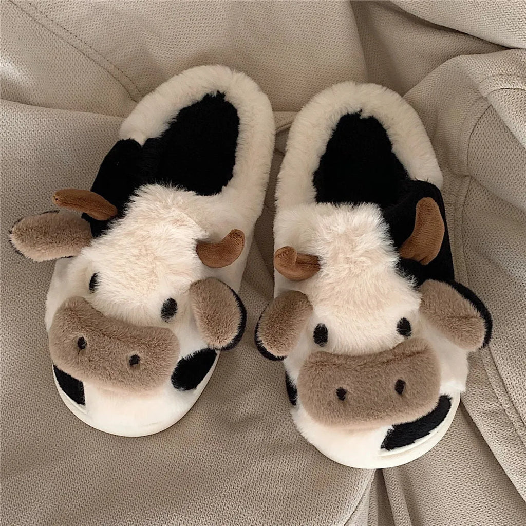 White cow-patterned plush slippers for women with a non-slip textured sole on a wooden floor