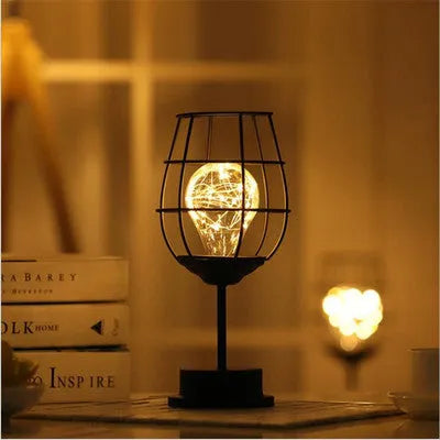 Minimalist wrought iron hollow table lamp in red wine glass style with warm white glow.