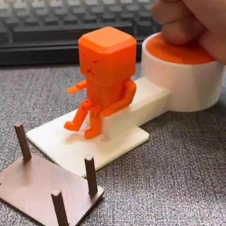 Orange plastic table-turning decompression toy on a desk.