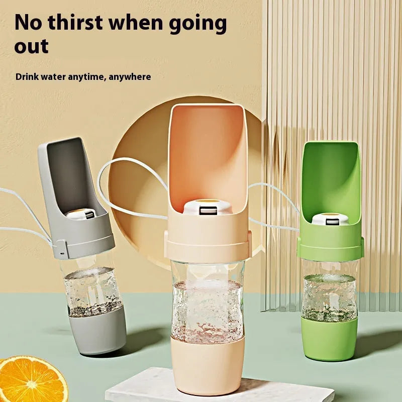 Grey folding travel dog water bottle with attached lanyard and separate food container, shown next to a backpack.