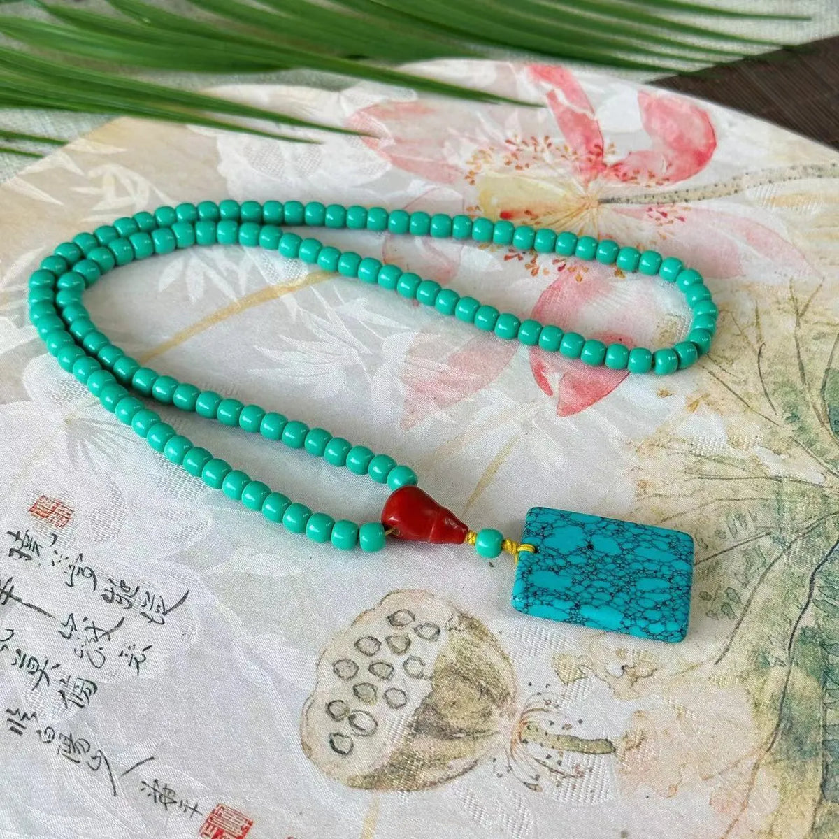Turquoise necklace with stone pendant on ball bead chain, showing mesh flower design