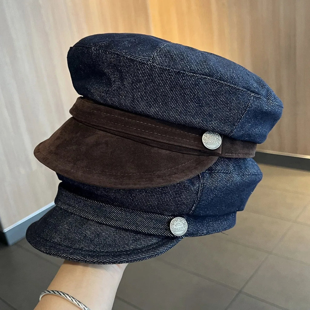Dark blue denim newsboy cap with an adjustable strap, shown on a model
