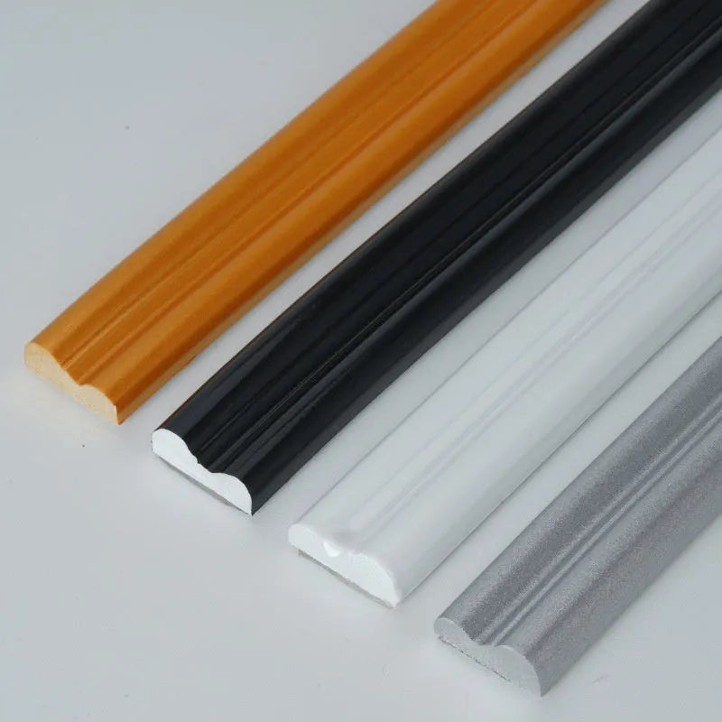 Flexible PVC self-adhesive background wall shaping frame on a white surface, showing black, gold, silver, and white colour options.
