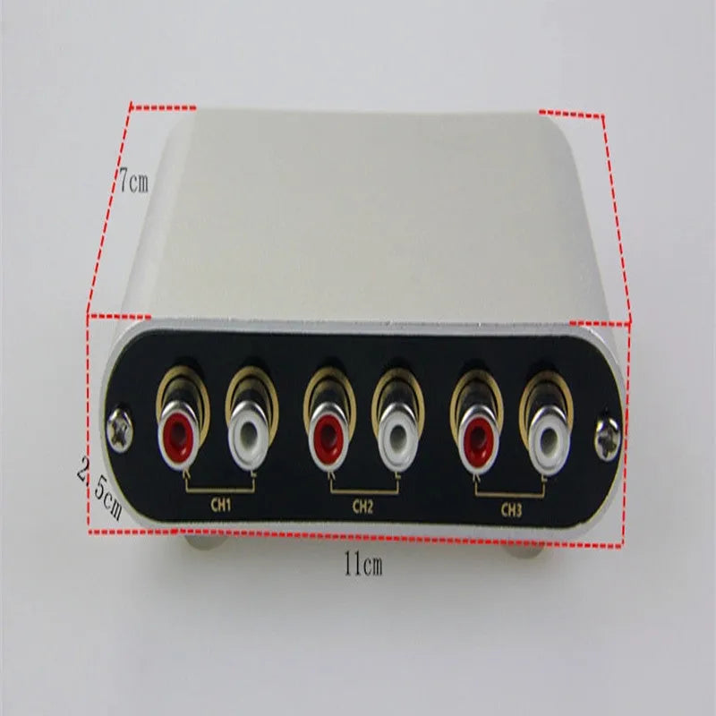 Silver aluminium audio source selector switch with infrared remote control on a shelf.