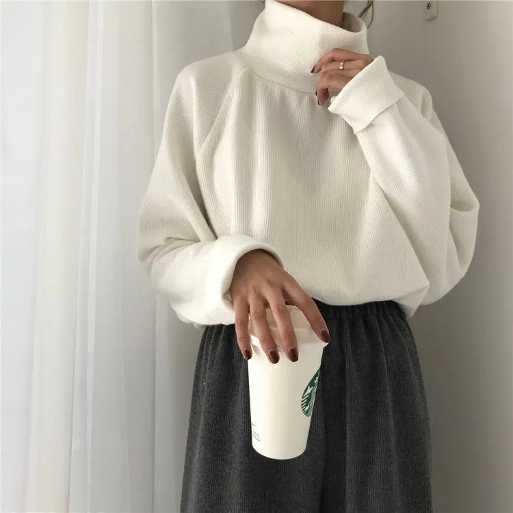 Woman wearing a solid apricot coloured loose fit long sleeve top with a half-high collar