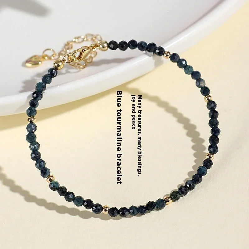 Close-up of a blue tourmaline beaded bracelet with metallic spacer beads on a woman's wrist.