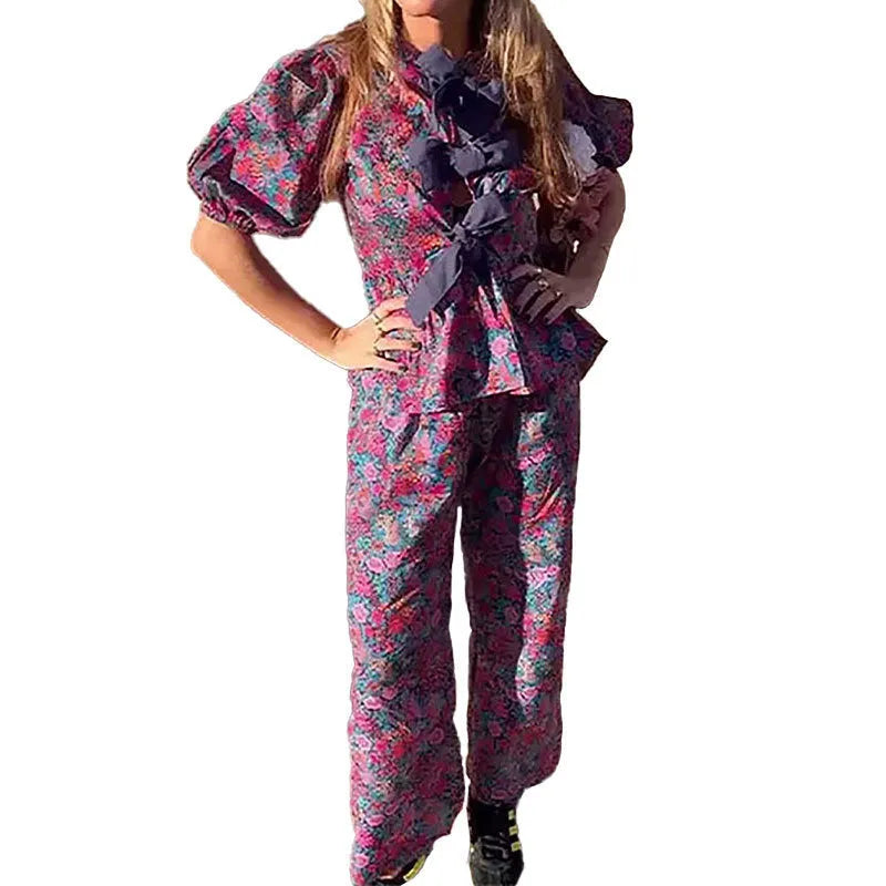 Women's floral print trousers suit with tie-neck blouse featuring puff sleeves and matching long trousers