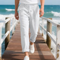 Men's light beige linen casual trousers with a drawstring waist and straight leg on a hanger.