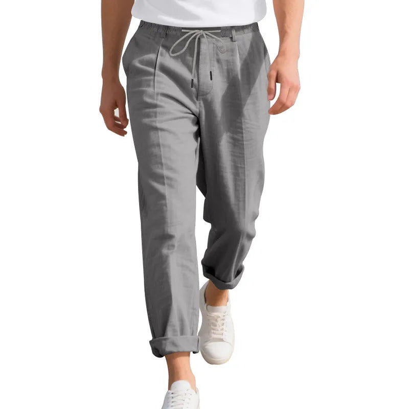 Men's light beige linen casual trousers with a drawstring waist and straight leg on a hanger.