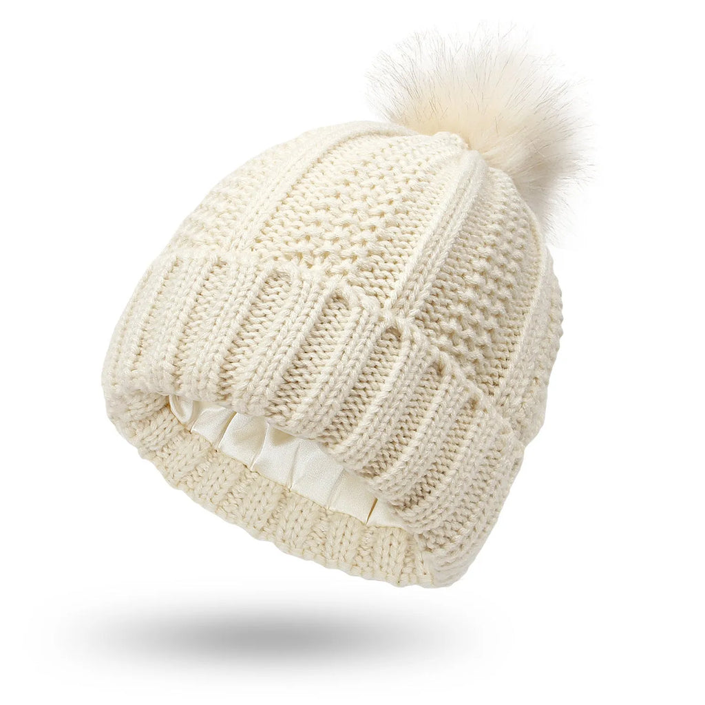 Women's knitted beanie hat with faux fur pom pom and satin lining in beige colour