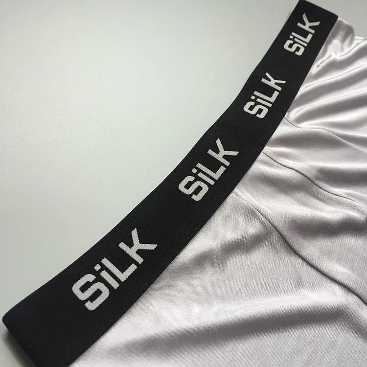 Men's loose fit silk shorts in navy blue on a neutral background