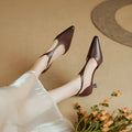 A pair of brown cowhide leather women's high heels with a pointed toe on a plain background.