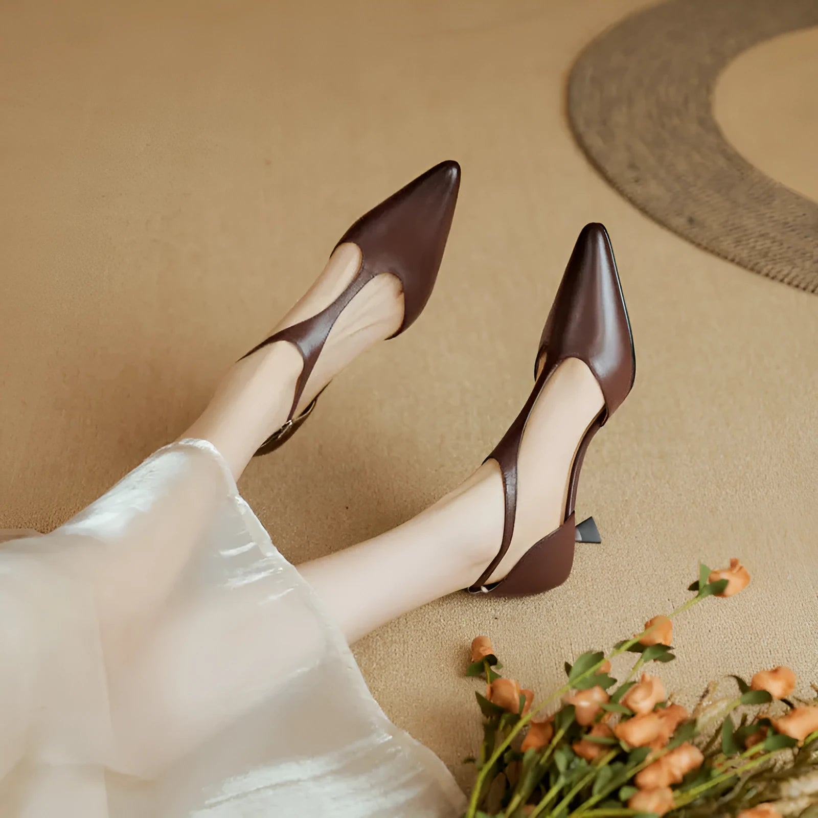 A pair of brown cowhide leather women's high heels with a pointed toe on a plain background.
