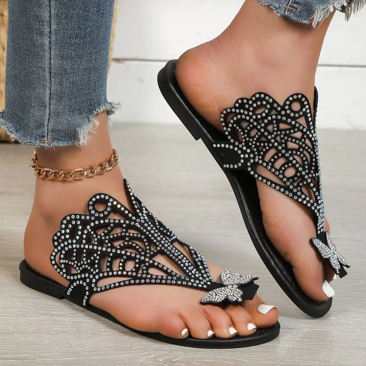 Women's black slip-on sandals with rhinestone details on hollow upper and flat rubber sole