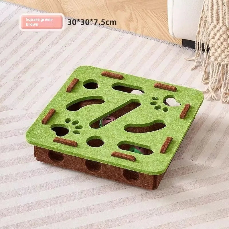 Green brown felt square cat toy with a hole in the centre on a wooden floor.
