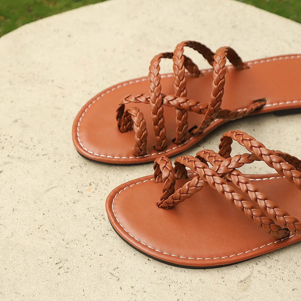 Women's brown woven Roman sandals with a clip-toe and flat rubber sole on a white background.