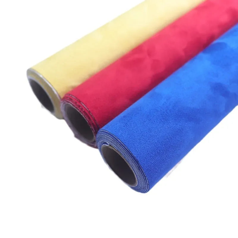 Roll of self-adhesive black leather suede fabric with adhesive backing visible, showing texture.