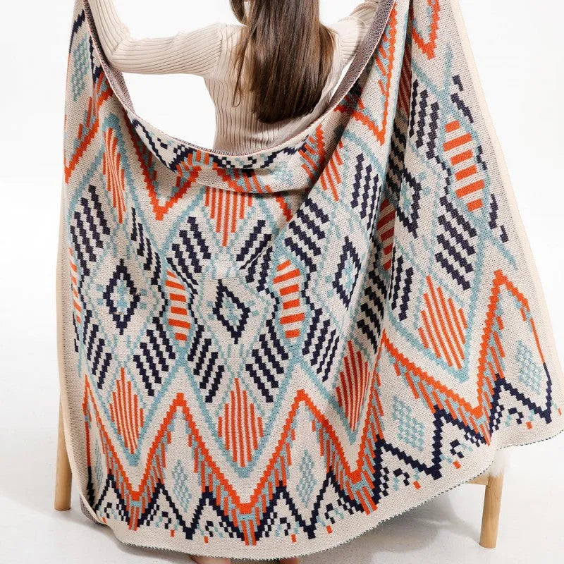 Bohemian style acrylic blanket with tassel fringe on a sofa, shown in a geometric print colour.