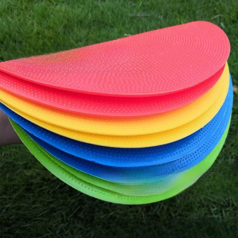 Flat yellow TPE football training landmark pad disc on grass, 23 cm in diameter.