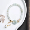 Jade green pearl bracelet with geometric pendant and peace buckle clasp on wrist