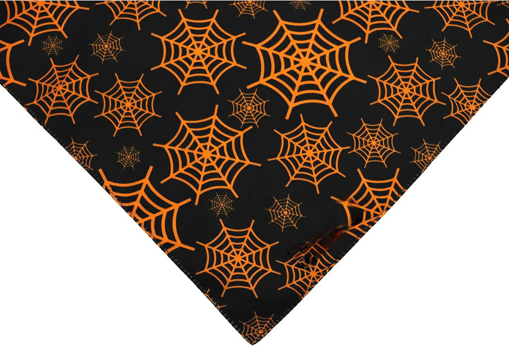 Black and orange reversible Halloween dog bandana with pumpkin and spider web patterns, showing adjustable fastening.