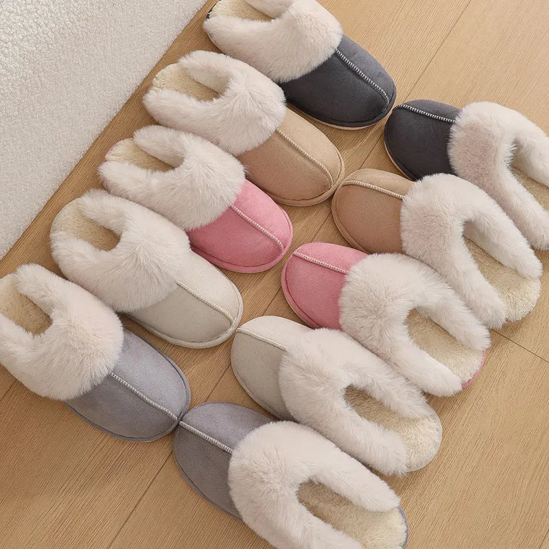 Women's brown plush winter slippers with round toe and flat heel on a wooden floor.