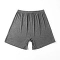 Man holding a pair of solid colour high-waist modal boxer shorts in dark grey.
