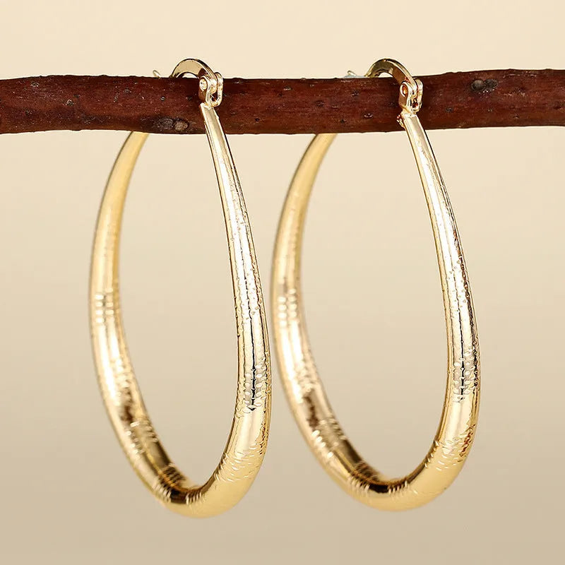 Geometric drop-shaped ear clips with ring and line design in metallic finish