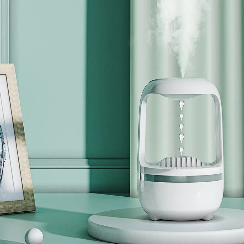 White anti-gravity humidifier on a table showing floating water droplets above its tank.