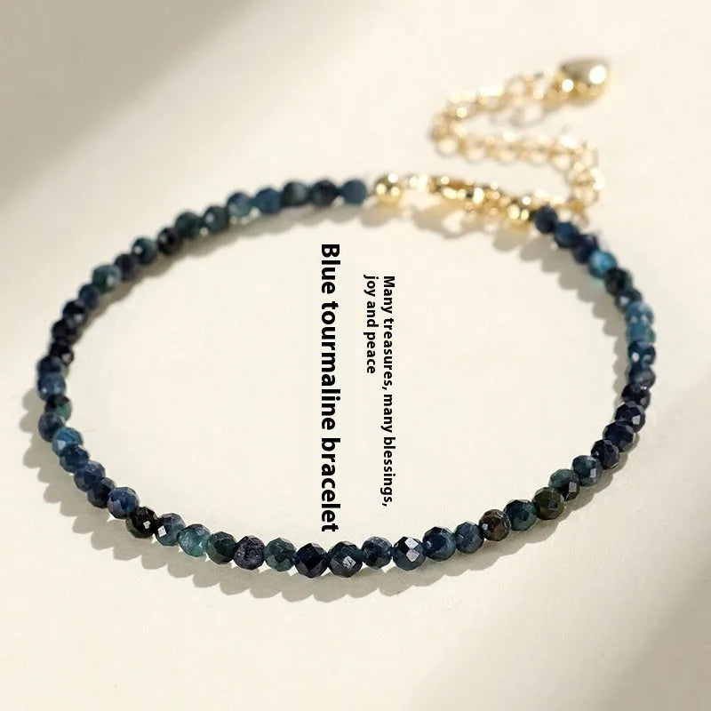 Close-up of a blue tourmaline beaded bracelet with metallic spacer beads on a woman's wrist.