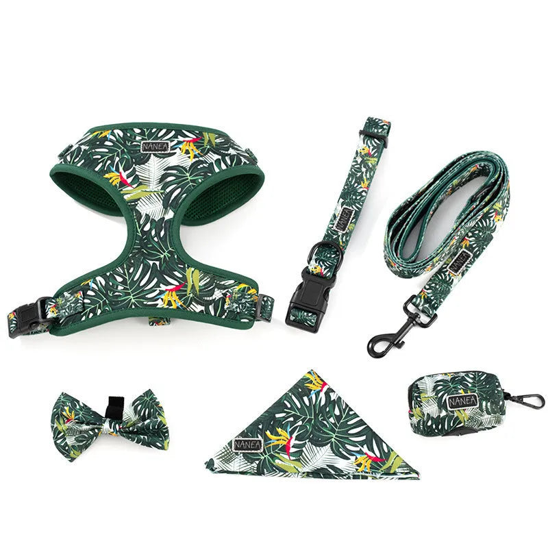 Six-piece adjustable cloth dog harness set on a table, showing vest, collar, rope, waste bag, bow, and triangular scarf.